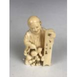 A Meiji Japanese carved ivory okimono depicting an entertainer carrying a series of double gourds