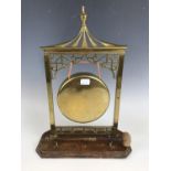 A late Victorian brass dinner gong, raised over an oak base, 40 cm