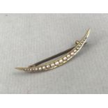 An Edwardian seed pearl brooch modelled in the form of a crescent moon, on high-carat yellow-