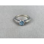 A contemporary diamond and blue topaz dress ring, the central oval-cut aquamarine, of