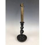 A Victorian candle-form oil lamp, having a brass tubular reservoir set upon an ebonised double-