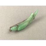 A 1920s jade brooch carved in depiction of a bird on a bough, claw set on gilt white-metal