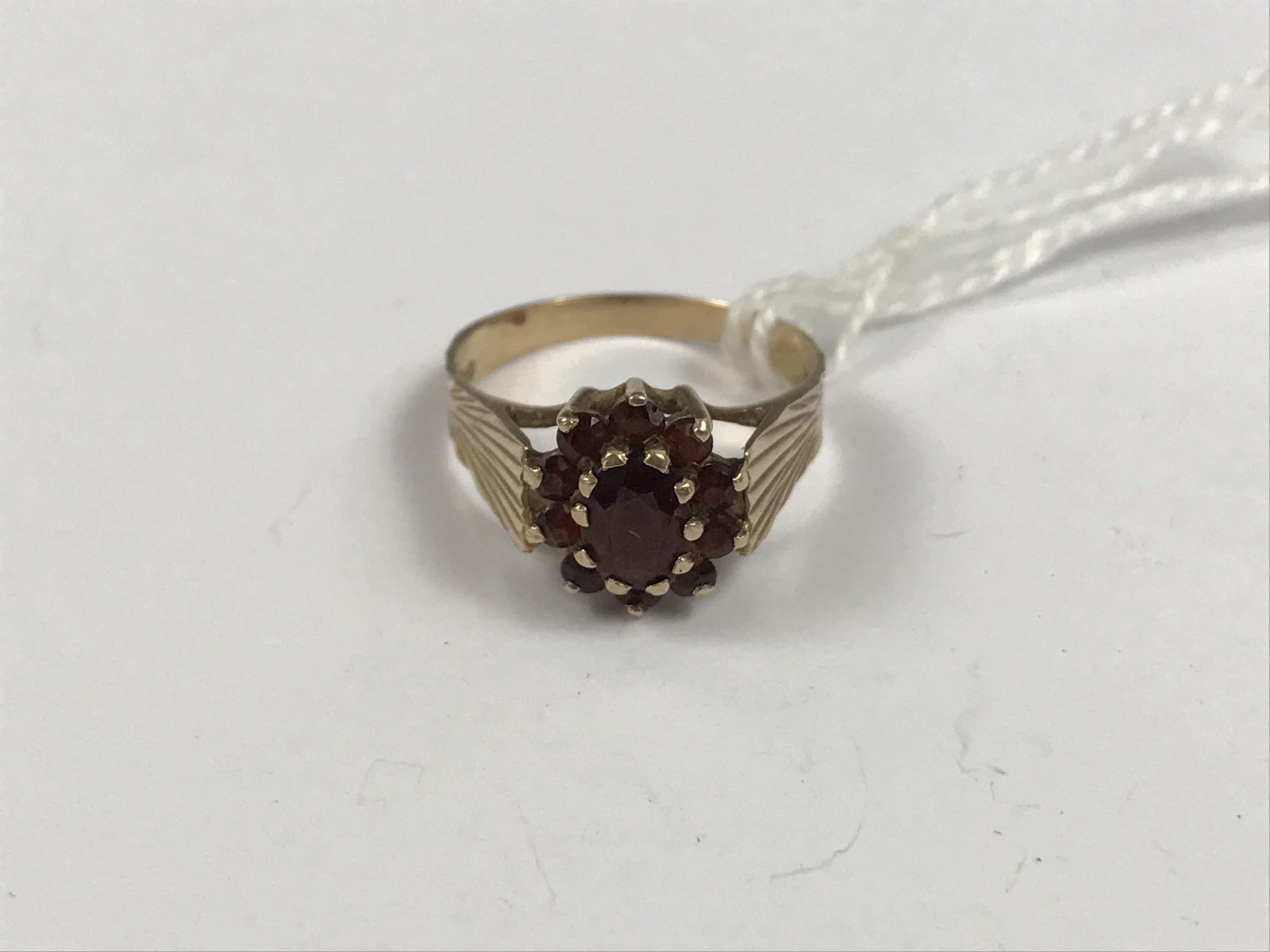 A 9ct gold and garnet dress ring, in a flower-head cluster arrangement over a radially-cut 9ct