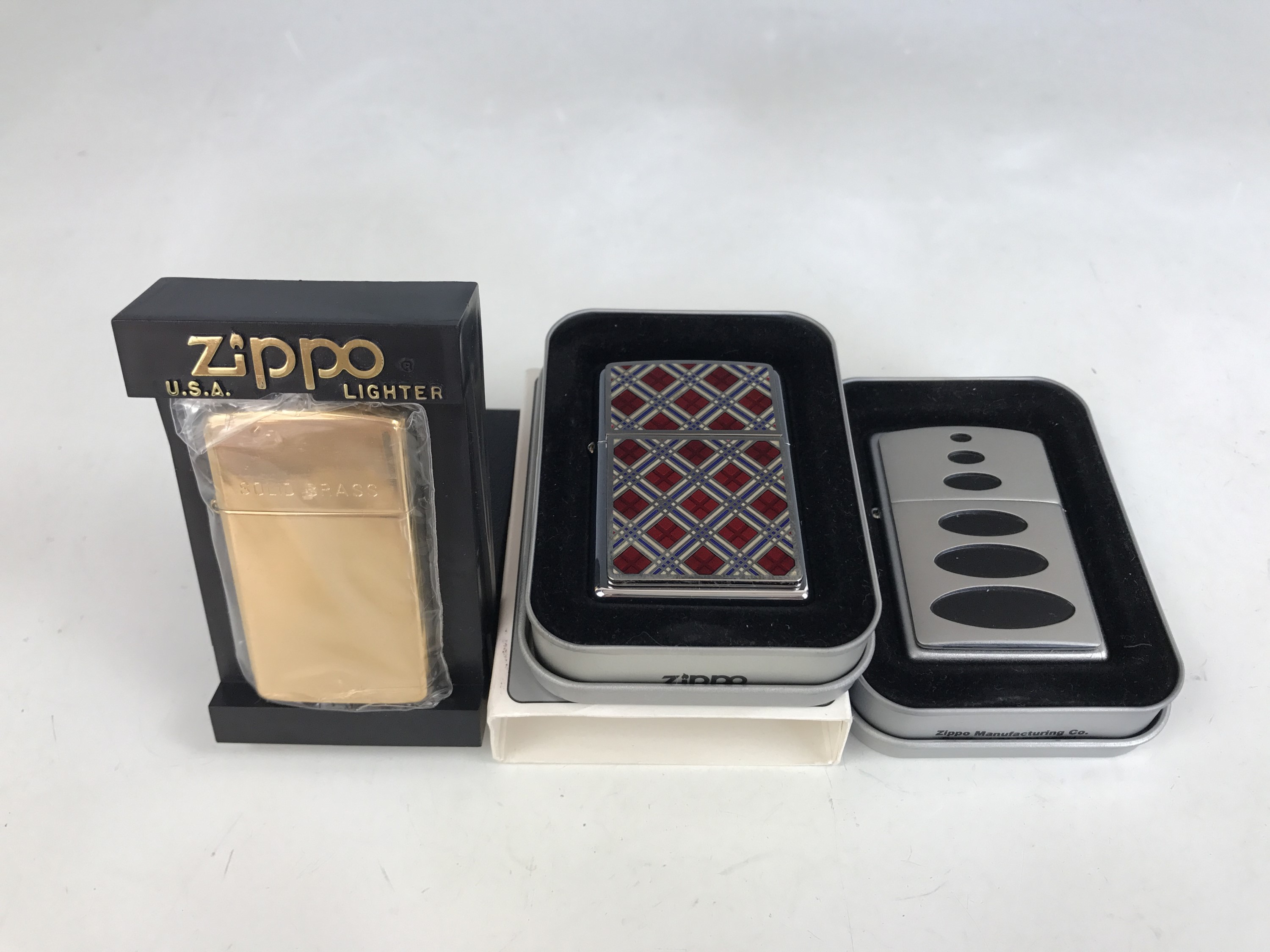 Three cased Zippo lighters, including 20429 Cherry Plaidness Emblem (not in original box) and one