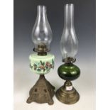 A cast metal and emerald green glass oil lamp together with one other similar