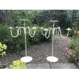 A pair of cream four-branch wrought iron candelabra / floristry stands