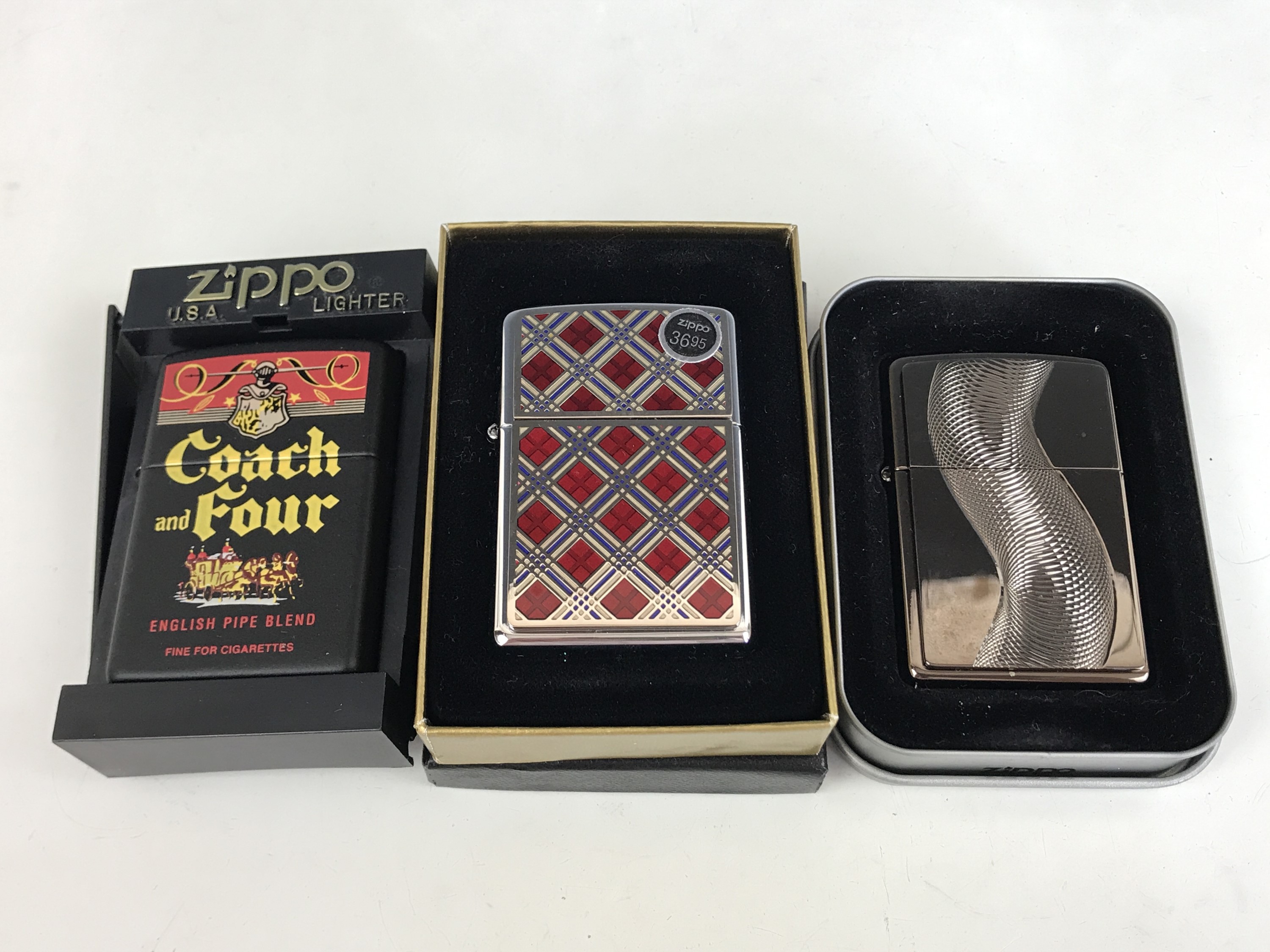 Three cased Zippo lighters, including the Coach and Four from the Tobacco Tin Series, and No.