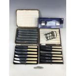 Three cased sets of tea knives together with an electroplate toast rack and set of Celtic napkin