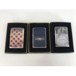 Three cased Zippo lighters, including No. 20429 Cherry Plaidness Emblem, No. 200 Blue and Chrome,