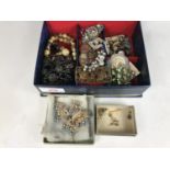 A blue faux leather jewellery box containing vintage costume jewellery, including two pairs of