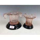 Two 1920s pink pressed-glass splash-form vases, raised on black glass socles