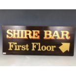 A painted wooden "Shire Bar, First Floor" sign, 38 cm x 92 cm