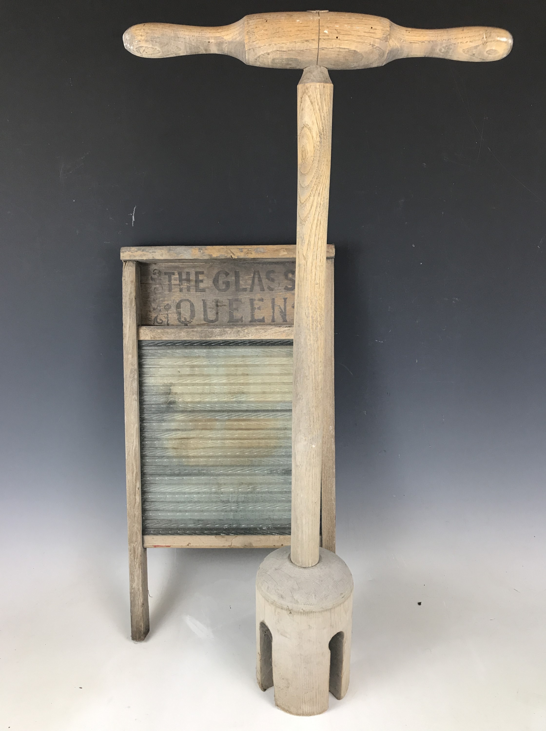 An antique wooden poss stick and glass scrubbing board