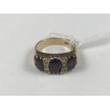 A 9ct gold and garnet dress ring, having three oval-cut garnets interspersed by three stones, 5.2g