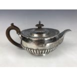 A Victorian silver tea pot, of compressed Georgian shape, having half-gadrooned decoration,