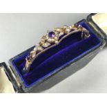 A Belle Epoque amethyst and pearl hinged bangle, having an open lenticular face surmounted by