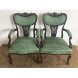 A pair of Victorian his-and-hers upholstered mahogany arm chairs