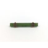 An early 20th Century yellow-metal and spinach jade bar brooch, the jade cut and polished to form