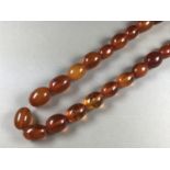 A single strand necklace of oval amber beads, beads approximately 20 x 15 mm and smaller, 80 cm,