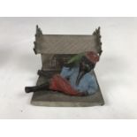 A novelty cold-painted cast-metal and tinplate money box, modelled as a recumbent figure reclining