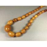 A single strand necklace of graded butterscotch amber beads, largest bead 24 x 17 mm, necklace 77 cm