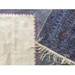 A woven Paisley shawl, having a cream field bordered by blue and red boteh, late 19th / early 20th