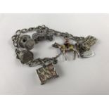 A vintage silver charm bracelet suspended with six white-metal charms, including a novelty folded