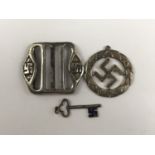 A white metal swastika pendant, a similar charm and buckle