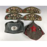 Four Cold War Soviet military caps, each set with numerous items of insignia, together with a
