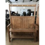 A contemporary bespoke pine settle with integral coat hooks and boot shelf, originally