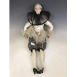 A boudoir doll dressed in a 1920s Pierrot costume, having a flocked and painted face, painted wooden