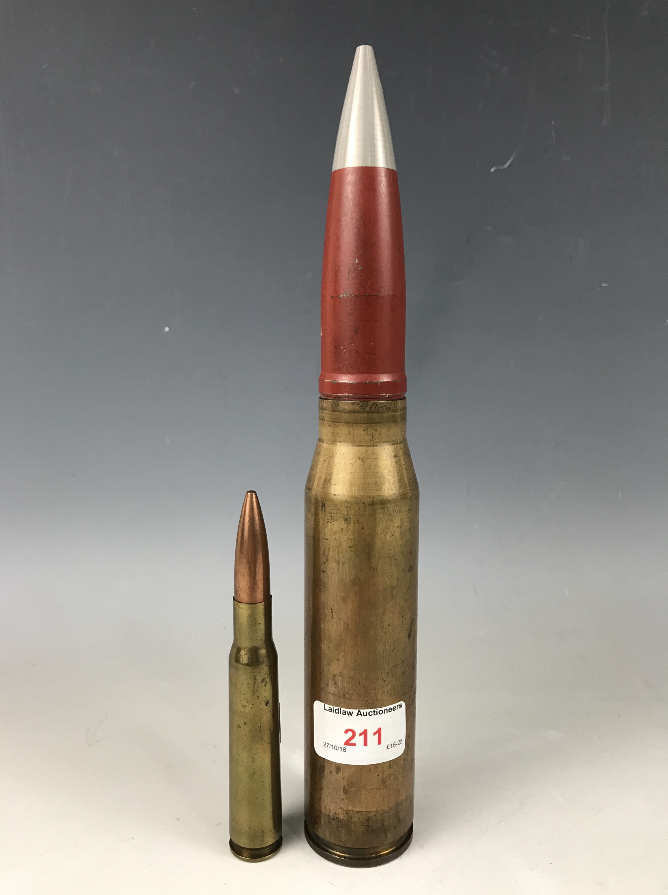 An inert brass 30mm round together with a brass half inch rifle round