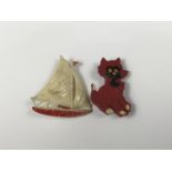 Two composition brooches, one depicting a comical cat, the other a yacht, circa 1920s - 1940s