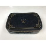 A vintage navy blue tooled-leather jewellery case, opening to reveal a quilted suede lining and