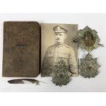 A Great War soldier's YMCO New Testament, together with three cap badges