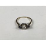 A 9ct gold three-stone dress ring, having a central oval-cut clear stone flanked by a pair of