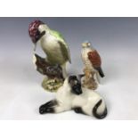 A Beswick kestrel, together with figurines of a Siamese cat and a woodpecker