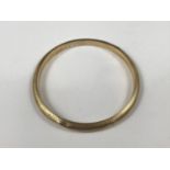 A yellow metal bangle, having engine-turned decoration, tests as gold, 10.6g