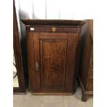 An early 19th century mahogany cross-banded and marquetry-inlaid oak hanging corner cabinet