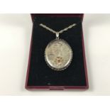 An Elizabeth II silver and almandine garnet pendant locket, engraved with foliage, the face