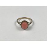 A 9ct gold and coral dress ring, the cabochon stone being rub and rope-twist set above a fine