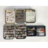 Three fly boxes and flies together with a tin of fishing hooks