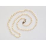 A vintage single-strand necklace of graded pearls, having a white-metal lenticular box-clasp stamped