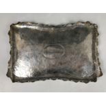 An Edwardian silver Arts and Crafts planished tray, having an everted wavy rim, and incised