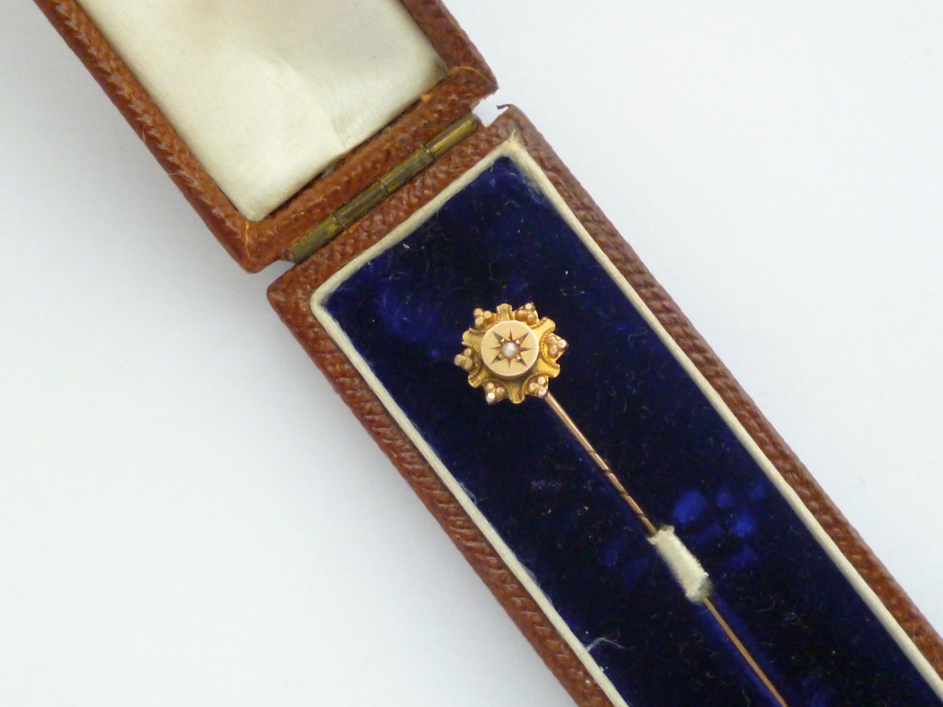 A late Victorian 9ct gold and split seed pearl stick pin, gypsy set within a pelleted and cannetille