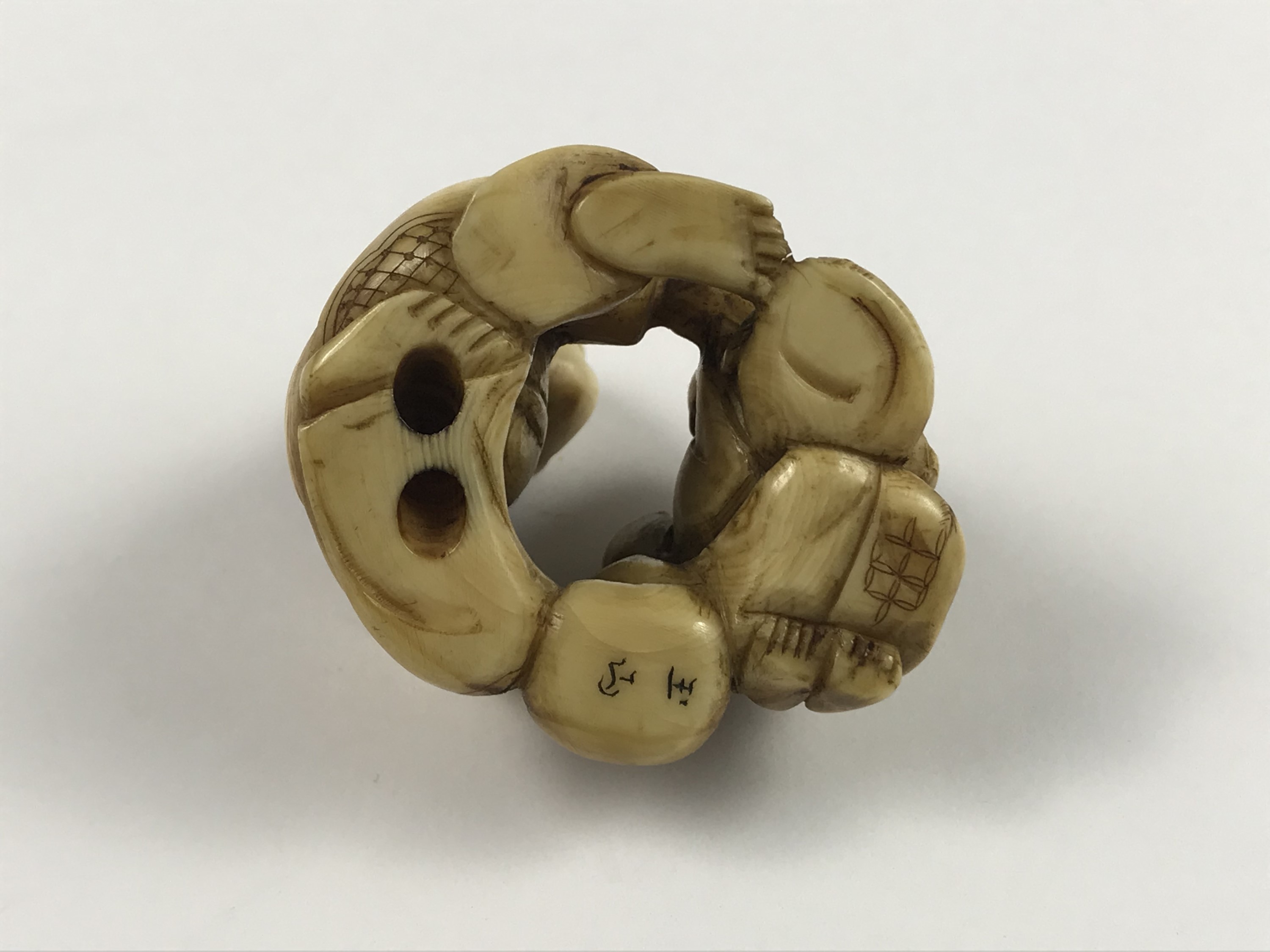 A Meiji Japanese carved ivory netsuke modelled as a crouching man giving assistance to a weary - Image 2 of 2