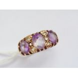 A 9ct gold and amethyst three-stone cocktail ring, having three oval-cut stones claw set in a graded