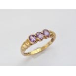 A 9ct gold and amethyst three-stone dress ring, the oval cut stones being collet set and flanked
