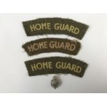 Three Home Guard cloth shoulder titles and a lapel badge