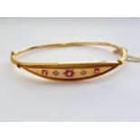 An Edwardian 9ct gold, ruby and diamond hinged-bangle, having a lenticular shaped face